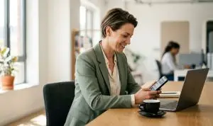 Dirigeante de PME utilisant LinkedIn sur smartphone dans son bureau
